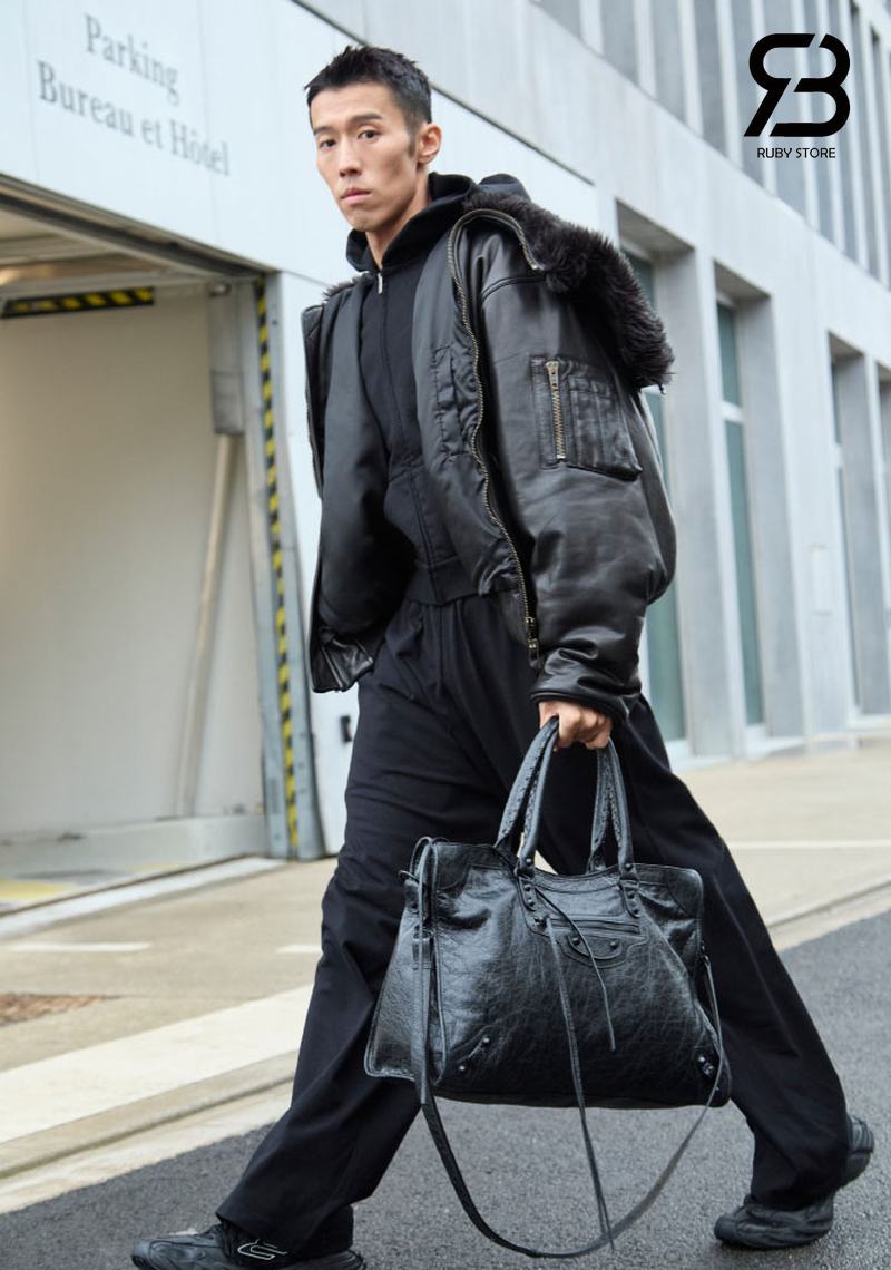 Nam đeo túi Balenciaga đen với outfit đen