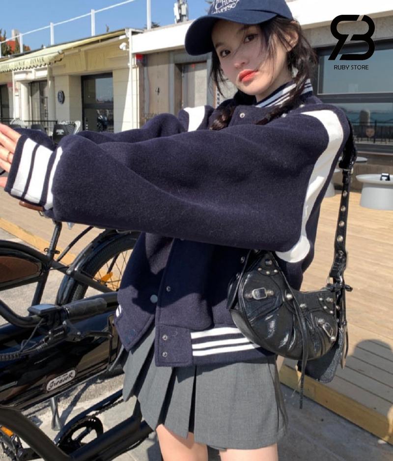 Nữ đeo túi Balenciaga màu đen với áo khoác varsity và váy ngắn